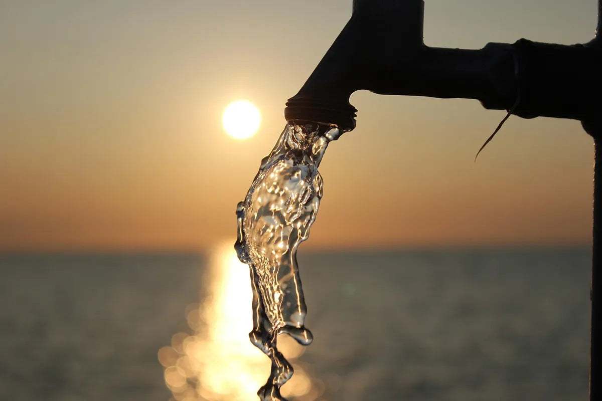 Eau jaillissant d'un robinet au coucher du soleil